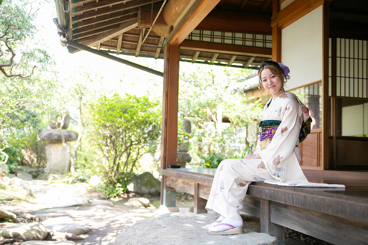 白い振袖の女性が縁側に座っている