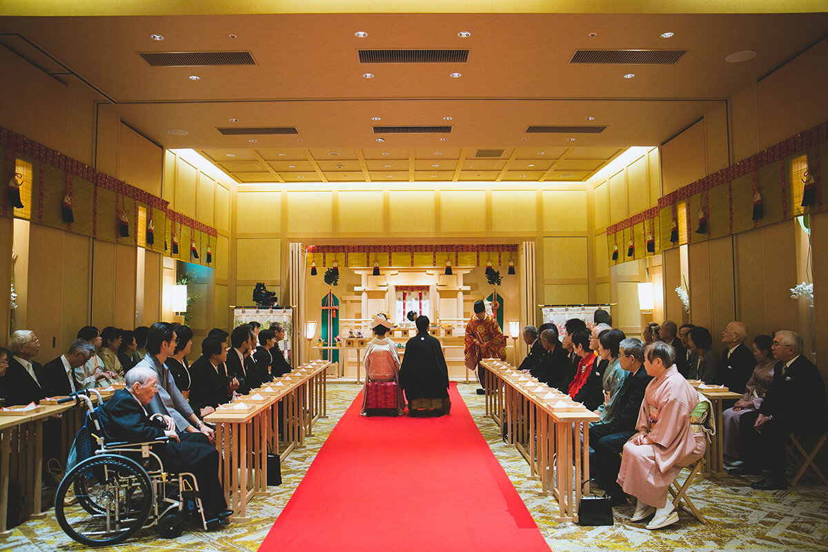 神前式の結婚式で、新郎が紋付羽織袴、新婦が色打ち掛けを着て、親族が着物を着ている